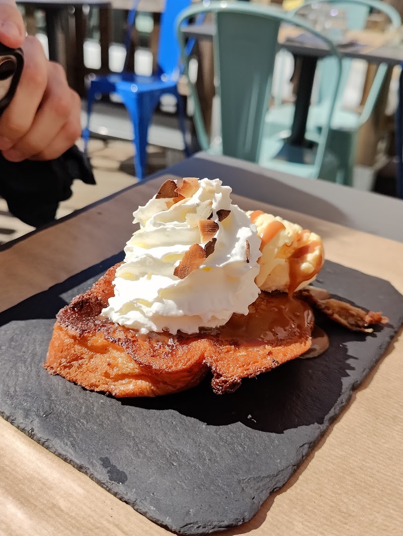 Une tranche de pain perdu servie sur une table en terrasse